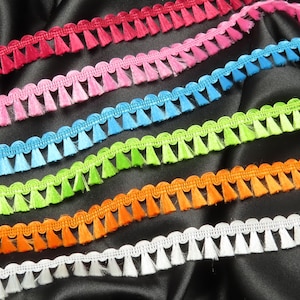 May include: Assortment of colorful trim with fringe, featuring a variety of colors including pink, blue, green, orange, and white.