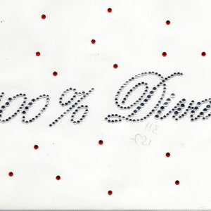 May include: White background with red dots and the words "100% Diva" spelled out in silver rhinestones.