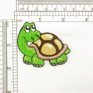 May include: Green and brown embroidered iron-on patch of a turtle carrying another smaller turtle on its back.
