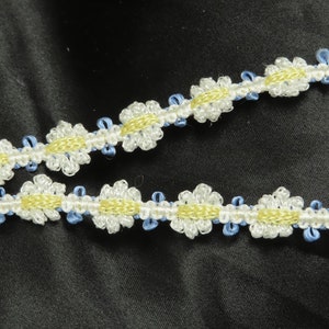 May include: White and yellow daisy trim with blue accents. The trim is made of a soft, flexible material and is perfect for adding a touch of whimsy to any project.