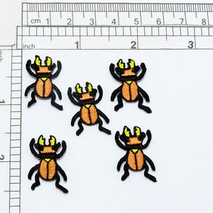 May include: Five iron-on patches of orange and black stag beetles with yellow accents. The beetles are approximately 1 inch in size.