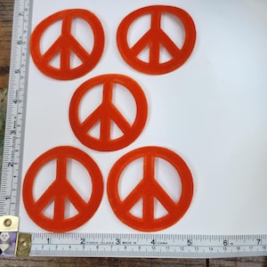 Peut inclure: Cinq symboles de paix en feutre orange, chacun mesurant environ 5 cm de diamètre.