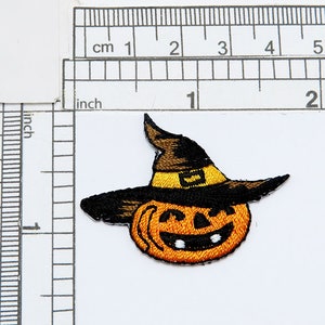 May include: An embroidered iron-on patch of a smiling orange pumpkin wearing a black witch hat with a yellow band.