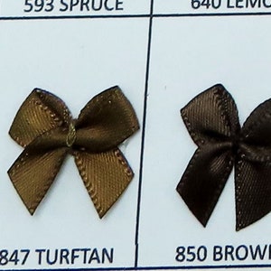 May include: Two brown satin bows, one a lighter brown with a gold sheen and the other a darker brown. The bows are labeled "847 TURFTAN" and "850 BROWN".