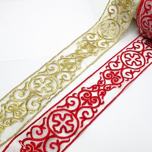 Könnte beinhalten: Zwei Rollen Dekorband mit einem komplizierten floralen Muster. Eine Rolle ist gold auf weiß, die andere rot auf weiß.