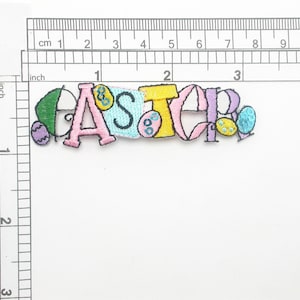 Op de afbeelding: Een kleurrijk geborduurd patch met het woord "EASTER" in roze, gele, blauwe en groene letters. De letters zijn versierd met kleine, kleurrijke, geborduurde eieren.