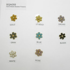 May include: A set of ten hand-made beaded flower embellishments in various colours, including gold, light gold, orchid, grey, blue, black, white, and rose.