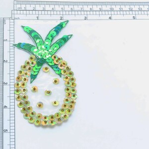 Può includere: Una toppa a forma di ananas verde e oro realizzata con paillettes. L'ananas è alta circa 12,5 cm.