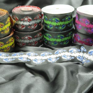 May include: Assortment of black fabric trim with colorful, patterned designs. The trim features a repeating wave pattern with different colors, including red, green, blue, and purple.