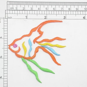 May include: An embroidered iron-on patch of an orange, yellow, blue, and green angelfish with a pink eye.