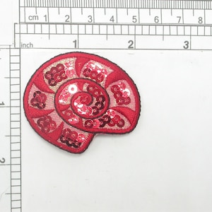 May include: Red and pink sequined seashell applique patch. The patch is about 2 inches wide.
