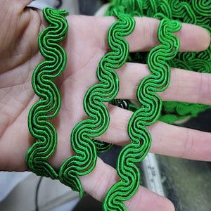 May include: Vibrant green wavy trim, a decorative textile element. The trim features a repeating, serpentine design. The image shows several strands of the trim, with a close-up view highlighting the texture and colour. Suitable for craft and sewing projects.