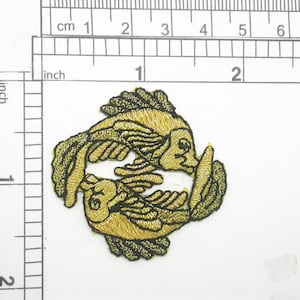 May include: Gold embroidered iron-on patch of two fish swimming in a circle. The fish are outlined in black thread.