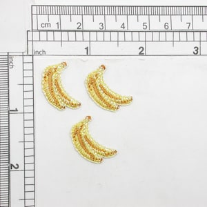 May include: Three yellow embroidered banana patches, each about 1 inch long, on a white background.