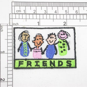 May include: A white patch with a green border and the word "FRIENDS" in black letters. Inside the patch are four stick figures drawn in different colors, with the word "FRIENDS" written below them.