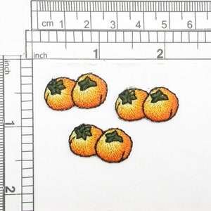 May include: Four embroidered orange persimmon fruit patches with green leaves.