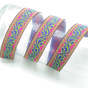 May include: A pink, green, and purple trim with a repeating pattern of stylized swirls. The trim is woven and has a gold thread running through it.