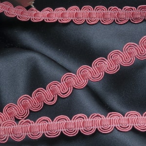 May include: A close-up of a red, decorative trim with a wavy, scalloped design. The trim is made of a soft, flexible material and is perfect for adding a touch of elegance to any project.