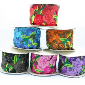 May include: Six spools of floral patterned ribbon in various colors, including red, blue, orange, gray, pink, and purple. Each spool is wrapped in white paper and features a floral design with green leaves.