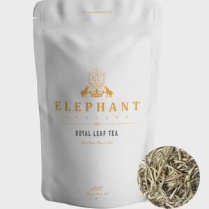May include: White pouch of Elephant Chateau Royal Leaf Tea with gold lettering and a circular inset of loose tea leaves. The pouch features a logo with elephants and a crown. The text "Royal Leaf Tea" is displayed prominently.
