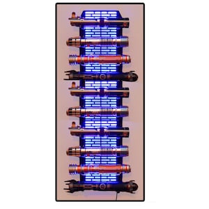 Puede incluir: Un expositor vertical con m&uacute;ltiples sables de luz. Los sables de luz son plateados, negros y rojos, montados en un marco negro con iluminaci&oacute;n LED azul. El expositor rectangular tiene un fondo blanco.