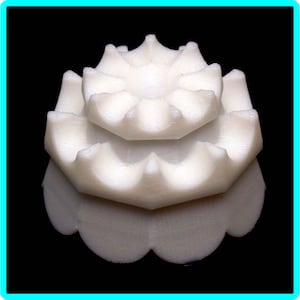 May include: A white 3D printed object with a layered, geometric design. The object has a circular base and a series of concentric rings that rise to a point.