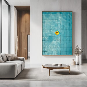 May include: A framed art print featuring a close-up view of a swimming pool with blue tiles and a yellow rubber duck floating in the water. The artwork is displayed in a modern living room setting.