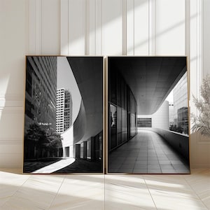 May include: Two framed black and white architectural prints. The left print shows a curved building facade with a skyscraper in the background. The right print depicts a long, curved walkway with a modern building.