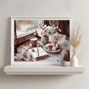 May include: A framed print featuring a still life scene. A cup of coffee, macarons, and a bouquet of flowers are arranged on a table near a window. A notebook and pen are also present, creating a cozy, inviting atmosphere.