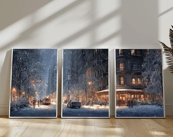 May include: Three framed art prints depicting a snowy city scene. The artwork shows buildings, streetlights, and vehicles on a snow-covered street. The prints are displayed on a wooden floor.