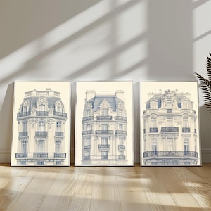 Puede incluir: Tres impresiones enmarcadas de dibujos arquitectónicos azules y blancos de edificios parisinos. Cada impresión presenta un edificio diferente con detalles intrincados y balcones.