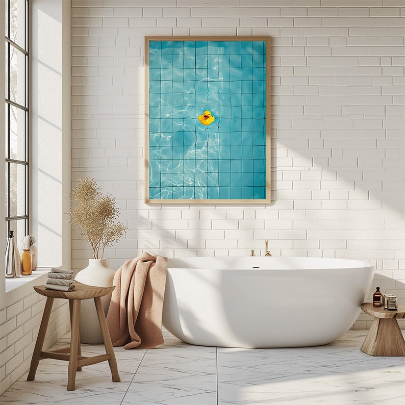 May include: A framed print featuring a yellow rubber duck floating in a turquoise blue pool. The pool has a grid pattern, and the print is displayed above a white bathtub in a bathroom setting.