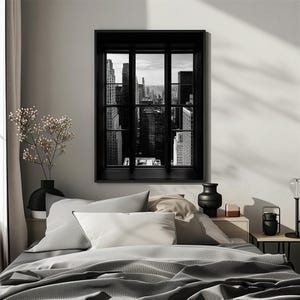 K&ouml;nnte beinhalten: Schwarz-Wei&szlig;-Druck eines Stadtbildes, das durch ein schwarzes Fenster betrachtet wird. Der Druck h&auml;ngt &uuml;ber einem Bett mit grauer Bettw&auml;sche und Kissen. Links im Bild befindet sich eine schwarze Vase mit Blumen.