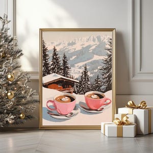 May include: A framed painting depicting a snowy mountain landscape with two pink mugs of coffee on a snowy surface. The mugs have a white foam design on top. The painting is in a gold frame.