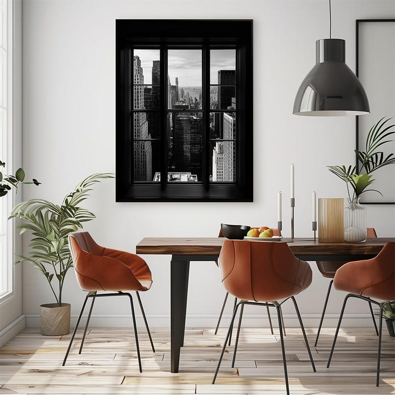K&ouml;nnte beinhalten: Schwarz-Wei&szlig;-Druck eines Stadtbildes, das durch ein Fenster betrachtet wird. Das Kunstwerk zeigt hohe Geb&auml;ude und Wolkenkratzer. Der Raum verf&uuml;gt &uuml;ber einen Holztisch, orangefarbene St&uuml;hle und eine h&auml;ngende schwarze Leuchte.