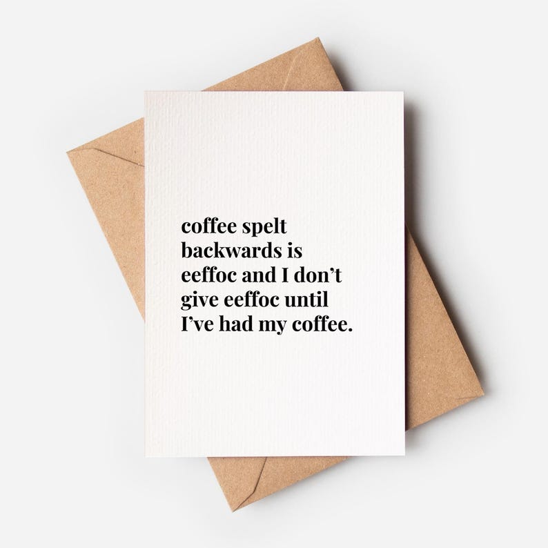 May include: A white greeting card with black text that reads: coffee spelt backwards is eeffoc and I don't give eeffoc until I've had my coffee. The card is placed on top of a light brown kraft paper envelope, creating a simple and clean contrast.
