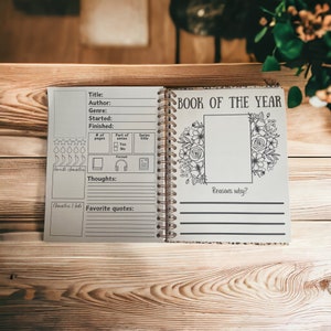 May include: A book of the year journal with a floral design on the cover. The journal has a section for title, author, genre, started, finished, number of pages, part of series, series title, format, thoughts, and favourite quotes. The journal also has a section for reasons why the book was chosen as the book of the year.