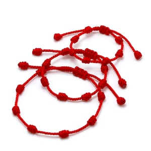 Op de afbeelding: Drie rode touw armbanden met verstelbare knopen. Elke armband heeft meerdere knopen langs de hoofdstreng en aan de uiteinden om de maat aan te passen. De armbanden worden tegen een witte achtergrond getoond.