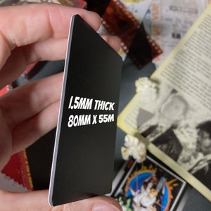 K&ouml;nnte beinhalten: Eine schwarze rechteckige Karte mit wei&szlig;en Kanten, gehalten in einer Hand. Die Karte misst 8 cm x 5,5 cm und ist 1,5 mm dick. Auf der Karte steht: "1.5MM THICK 80MM X 55M".