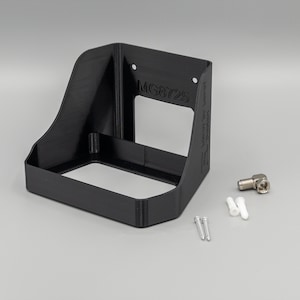 May include: A black, angled bracket with the text "MG8725" is shown. Included are two screws, two white wall anchors, and a silver-colored coaxial cable connector. The bracket has a rectangular opening and is designed to mount to a wall.