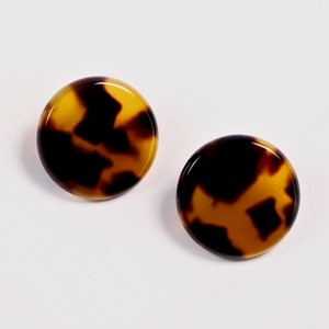 Può includere: Un paio di orecchini rotondi in tartaruga marrone e nero.