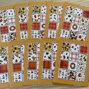 May include: A collection of ten rectangular greeting cards featuring a grid pattern of autumn-themed illustrations. Each card displays a mustard yellow border surrounding a collage of sunflowers, orange plaid squares, fall leaves, and pumpkins.