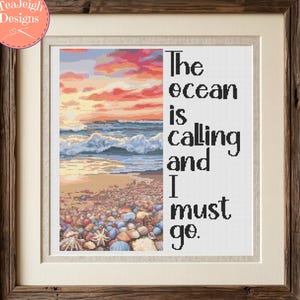 May include: A framed cross-stitch pattern featuring a sunset over an ocean beach with scattered seashells in the foreground. The text reads, The ocean is calling and I must go. The design is enclosed in a rustic dark brown wooden frame with a cream mat.