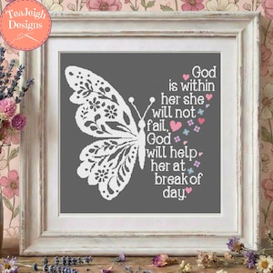 Op de afbeelding: Een ingelijst kruissteekpatroon met een witte vlinder met bloemrijke vleugeldetails op een donkergrijze achtergrond. De tekst luidt: God is within her she will not fail, God will help her at break of day, versierd met kleine roze en blauwe hartjes.