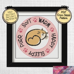 May include: A framed cross-stitch pattern with a sleeping cat in tan and cream, encircled by the words "Soft, Warm, Happy, Sleepy, Purr." The design includes paw prints on a white background, within a black frame. The image includes the text "PDF Cross Stitch Pattern."
