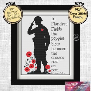 Op de afbeelding: Een zwart-wit cross-stitch patroon met een silhouet van een soldaat die salueert met rode klaprozen op de voorgrond. De tekst luidt "In Flanders Fields the poppies blow between the crosses row on row.  Lt Col John McCrae".