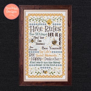 Peut inclure: Une affiche encadrée sur le thème des abeilles. L'œuvre présente les mots "Hive Rules" et d'autres phrases liées aux abeilles, ainsi que des illustrations d'abeilles, de fleurs et de motifs en nid d'abeille. Le cadre est de couleur marron foncé.