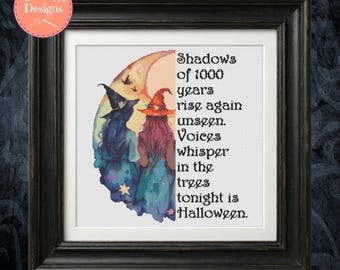 May include: A framed cross-stitch pattern featuring two figures in pointed hats standing before a crescent moon. The text reads: Shadows of 1000 years rise again unseen. Voices whisper in the trees tonight is Halloween. The design uses blue, orange, and yellow.