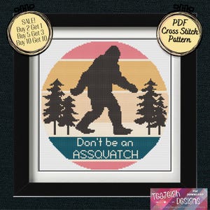 May include: Cross-stitch pattern featuring a black silhouette of Bigfoot walking in front of a sunset design with pine trees. The text "Don't be an ASSQUATCH" is below the image. The framed artwork is a PDF download.