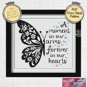 Może przedstawiać: Wzór haftu krzyżykowego w czerni i bieli przedstawiający motyla z tekstem "A moment in our arms forever in our hearts". Motyl jest otoczony małymi kolorowymi motylami.